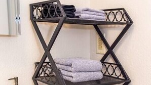 Een badkamer met een zwarte metalen handdoekhouder met opgevouwen handdoeken.