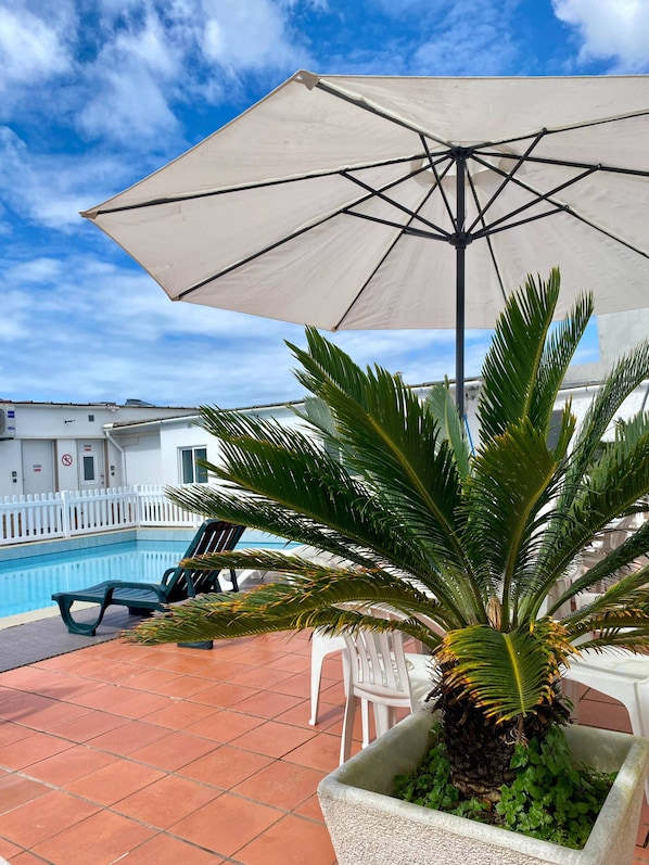 Relax by the pool surrounded by lush greenery and a secure white fence.