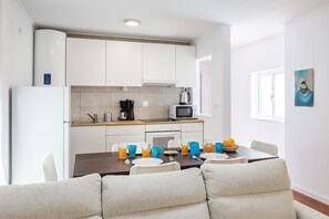 Enjoy meals in the fully equipped kitchen with microwave and kettle, adjacent to a dining area with a table for two.