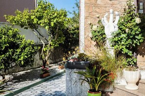 Stroll through the serene garden, surrounded by lush potted plants and a striking sculpture.