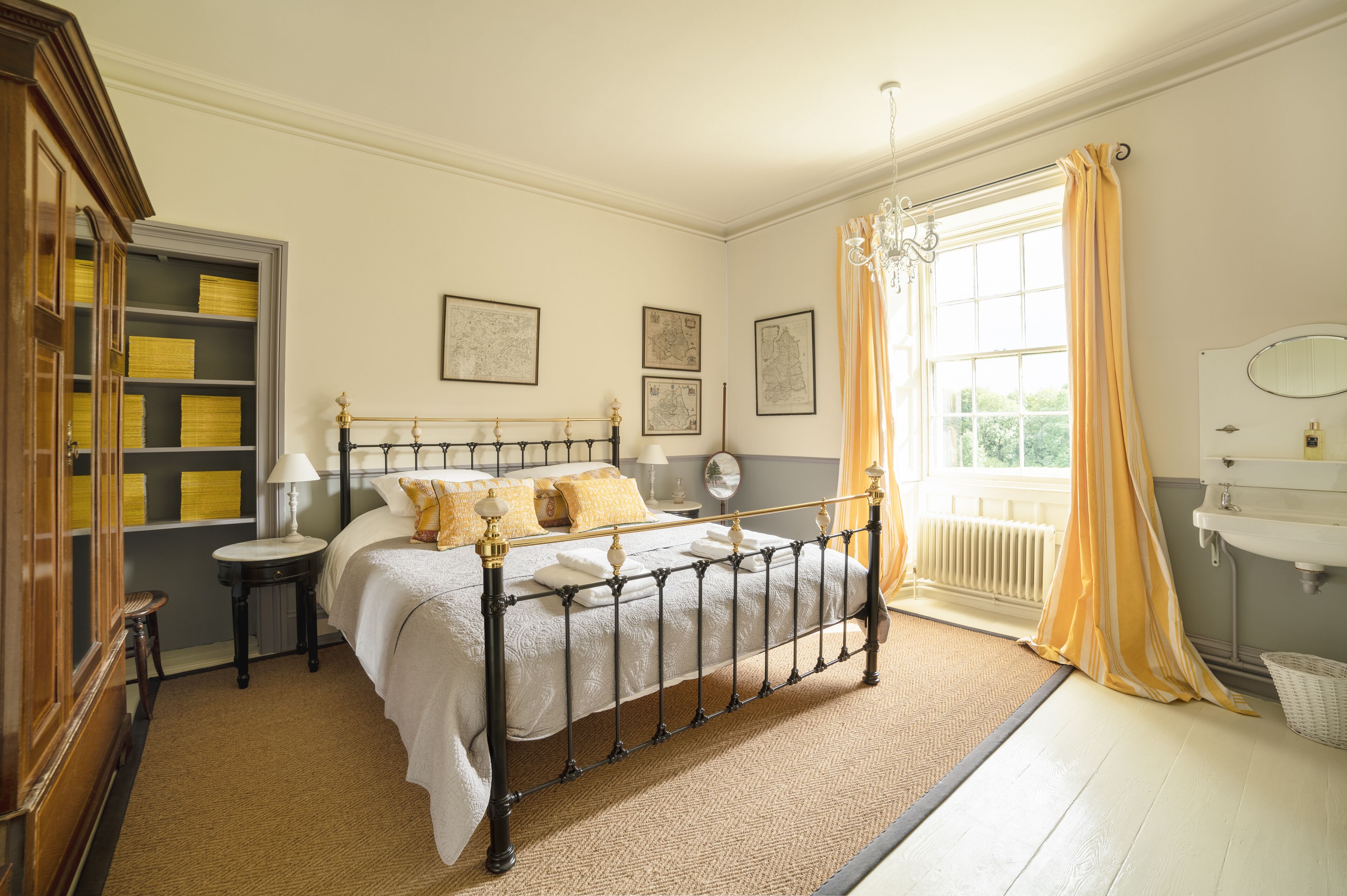 A neatly arranged bedroom with a bed, bedside tables, a dresser, and a window with curtains.