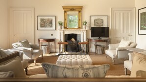 Ein Wohnzimmer mit gestreiften Sofas, einem Kamin und gerahmten Kunstwerken an den Wänden.