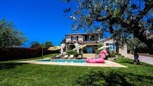 Una casa con piscina, mobiliario exterior y un flotador con forma de flamenco rosa.