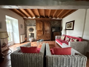 A living room with wicker furniture, a red sofa, and a stone fireplace.