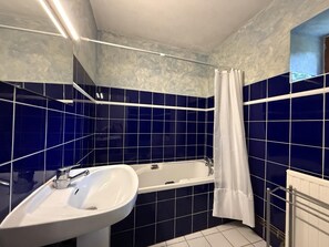 A bathroom with a bathtub, a sink, and a shower curtain.