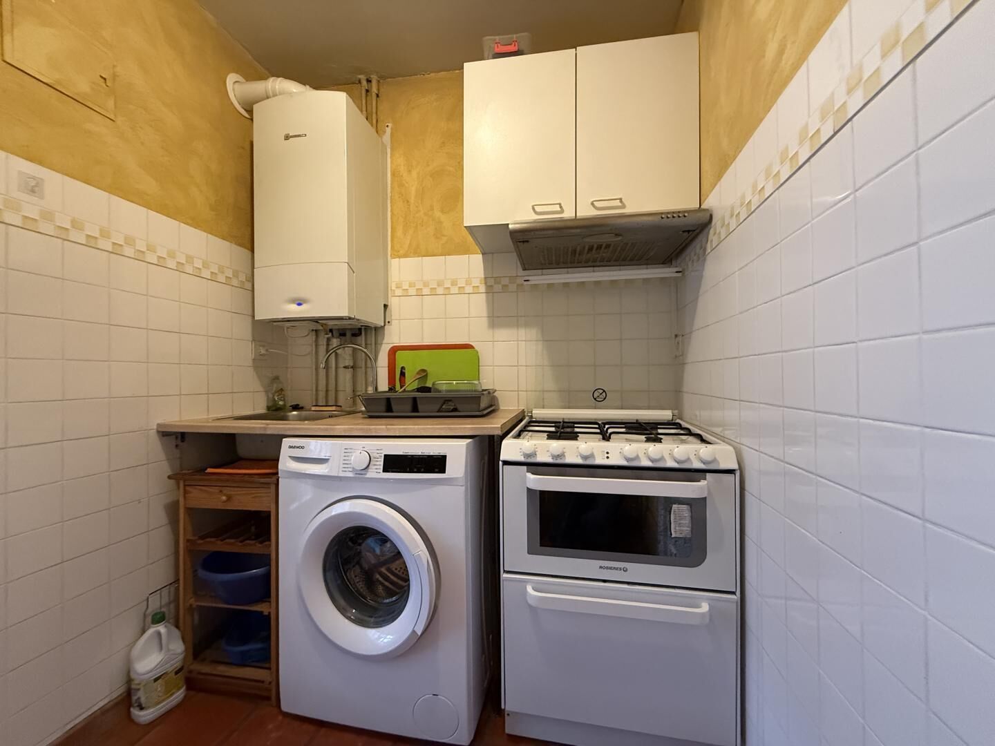 Una cocina compacta con lavadora, horno y cocina a gas.