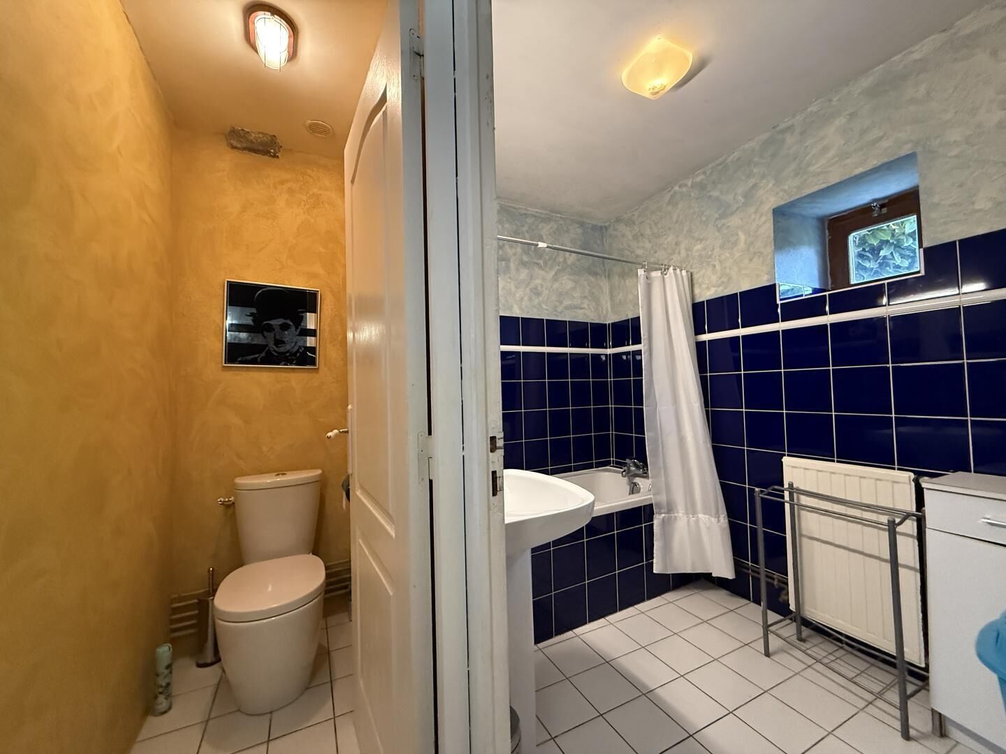 A bathroom with a toilet, sink, and shower area, featuring blue and beige tiles.