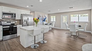 A modern kitchen with white cabinets, stainless steel appliances, and a central island with bar stools.