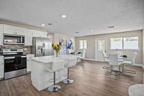 A modern kitchen with white cabinets, stainless steel appliances, and a central island with bar stools.
