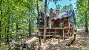 A cabin with a deck, surrounded by trees. - Woodland Hot Tub Retreat for Families and Friends (Broken Bow)