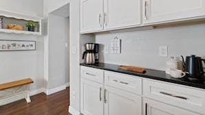 A kitchen with white cabinets, a black countertop, and a coffee maker.