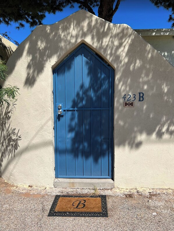 Una puerta azul con un ojo de cerradura, un buzón y el número 423 B.
