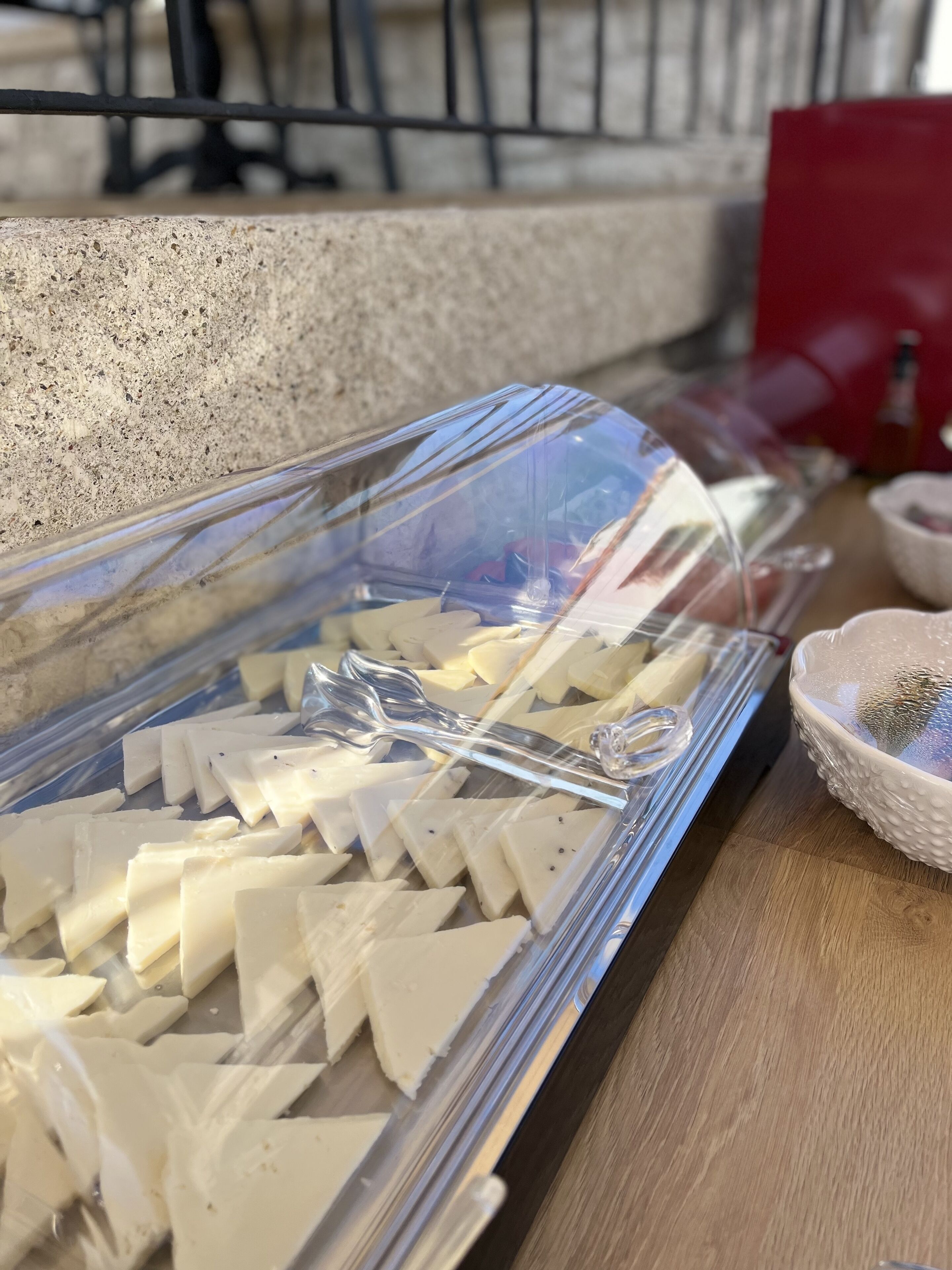 A clear plastic container with white triangular cheese pieces on a wooden surface.