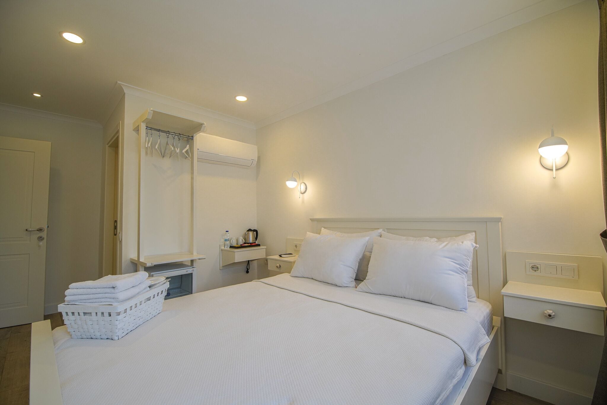 Una camera d'albergo ben ordinata con un letto grande, un comodino, una lampada a parete e un armadio.