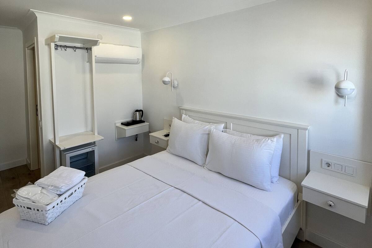 Habitación de hotel impecable con una cama grande, una mesita de noche, un espejo y un aplique de pared.