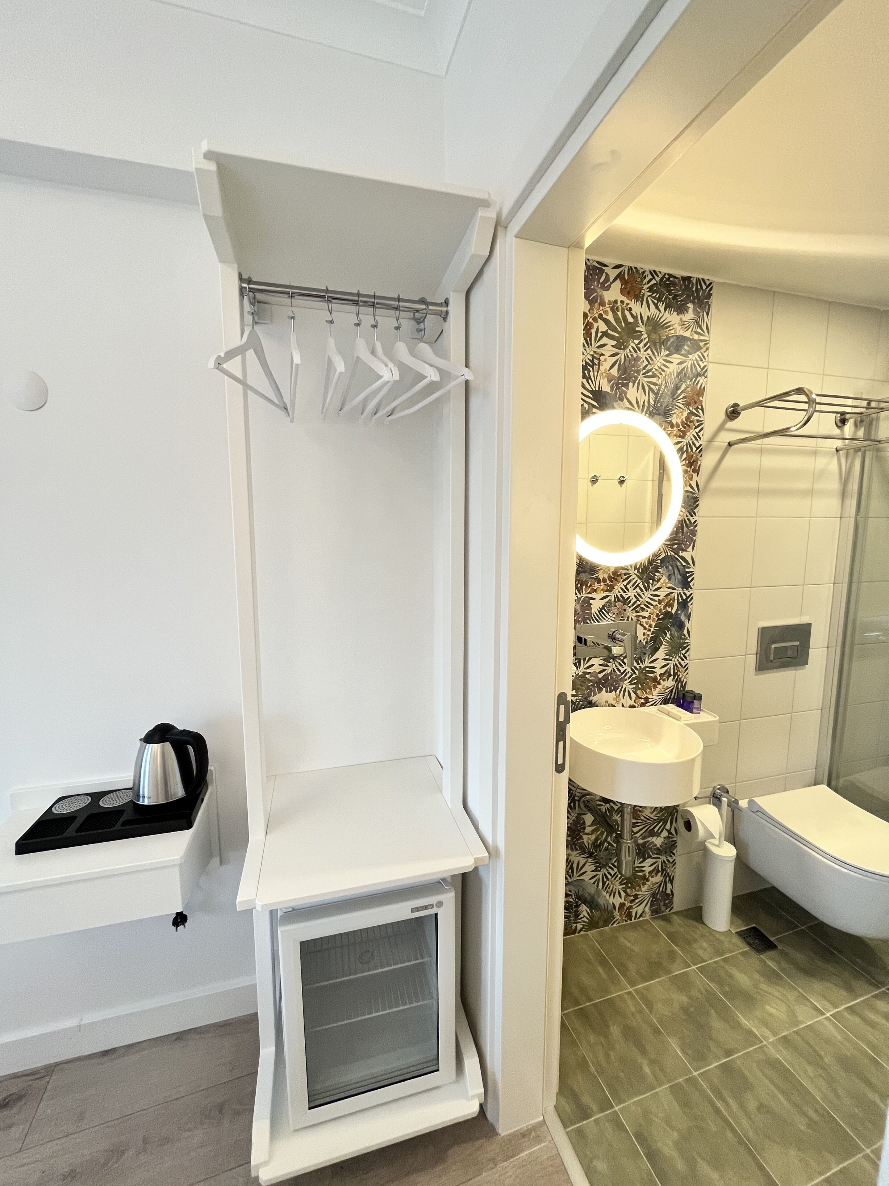 A modern bathroom with a built-in oven, a vanity with a mirror, and a shower area.