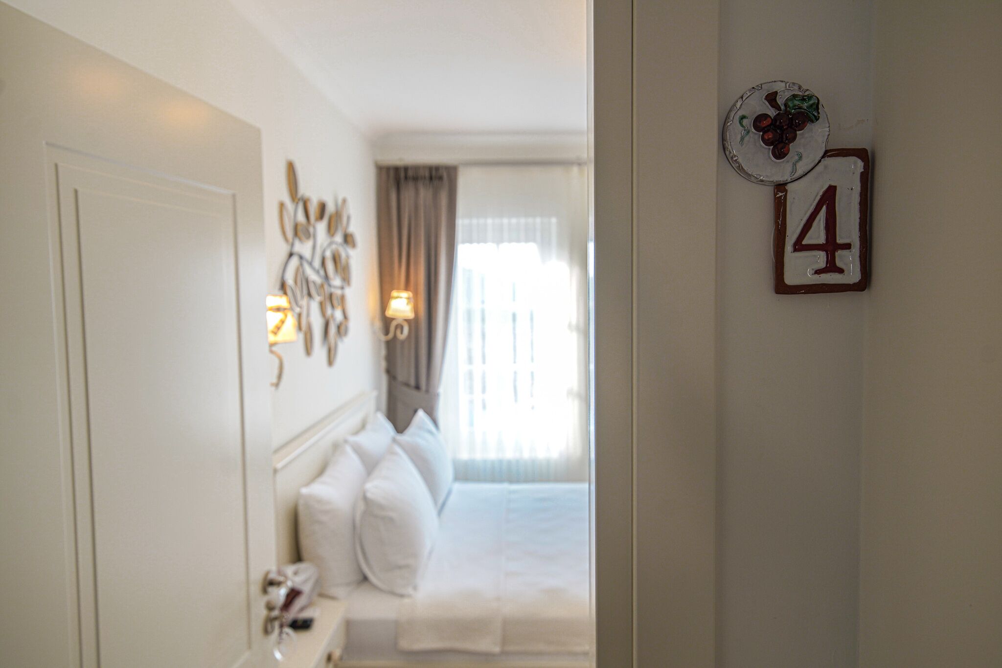 A hotel room with a bed, a bedside table, and a wall-mounted number '4'.