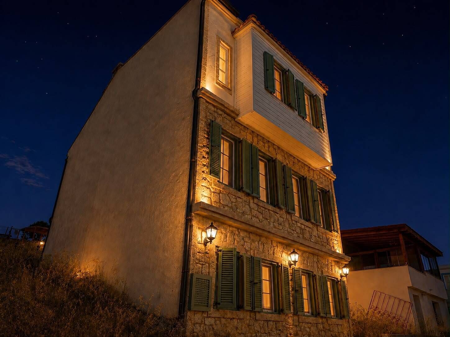 A two-story building with stone facade, green shutters, and multiple windows.