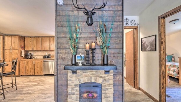 A fireplace with a deer head decoration, surrounded by tall grasses and candles. - 'Raven Hill Retreat' ~ Close to Midtown! (Ruidoso)