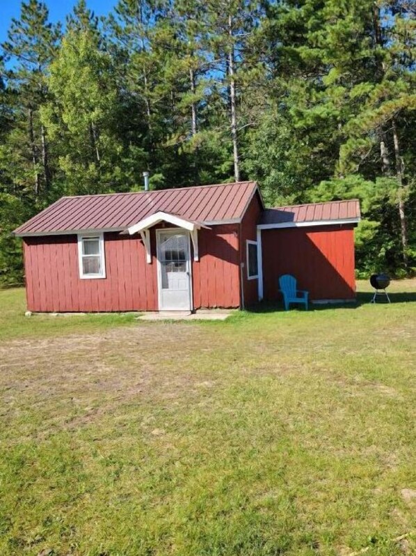 A small red wooden cabin with a metal roof, a front door, and a small porch. - Private Cabin 2 between munising and manistique (Manistique)