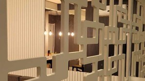A modern interior with a geometric white partition, a sofa, and a dining area with a table and chairs.