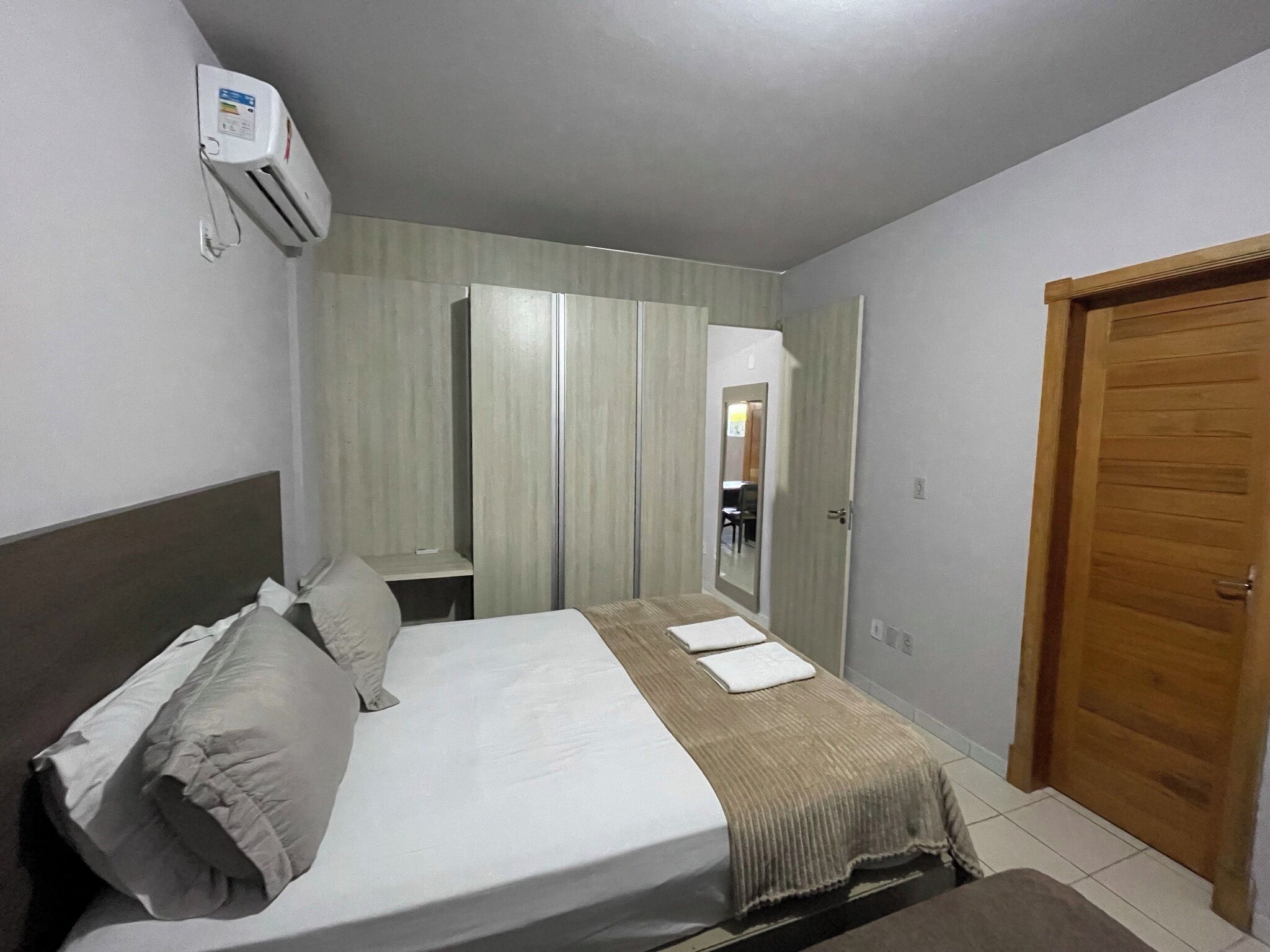 A bedroom with a bed, a wooden door, and a mirror.