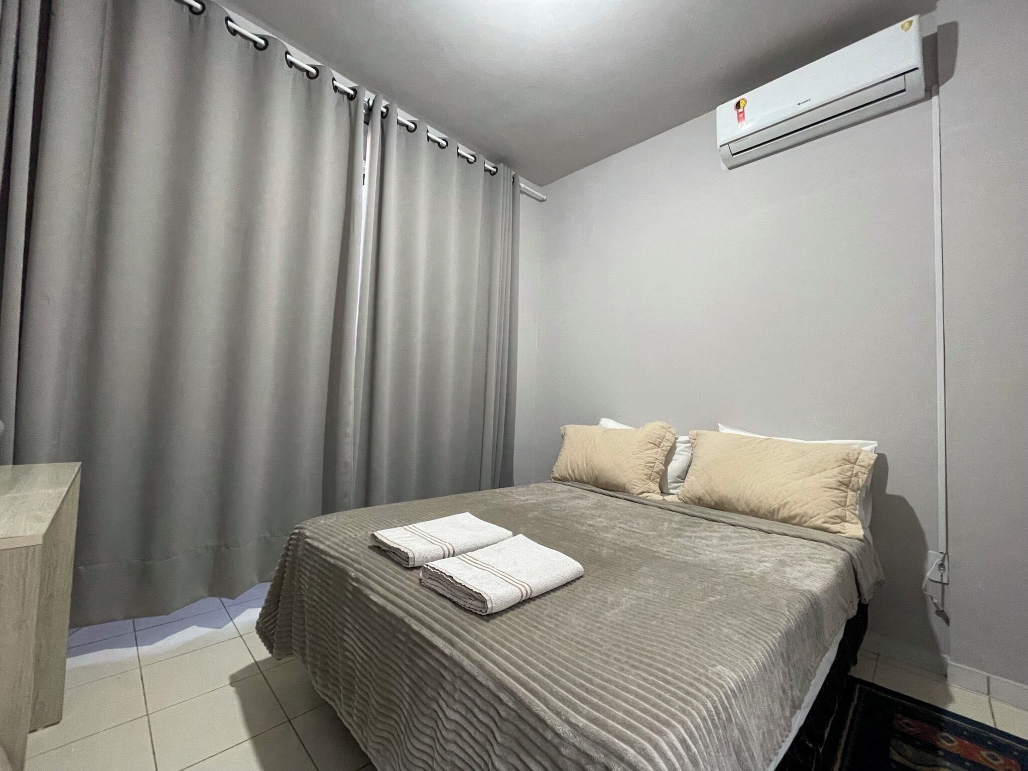A bedroom with a bed, pillows, a bedside table, and a curtain.