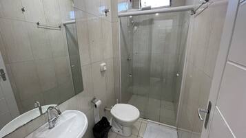 Casa de banho moderna com lavatório, sanita e cabine de duche com vidro.