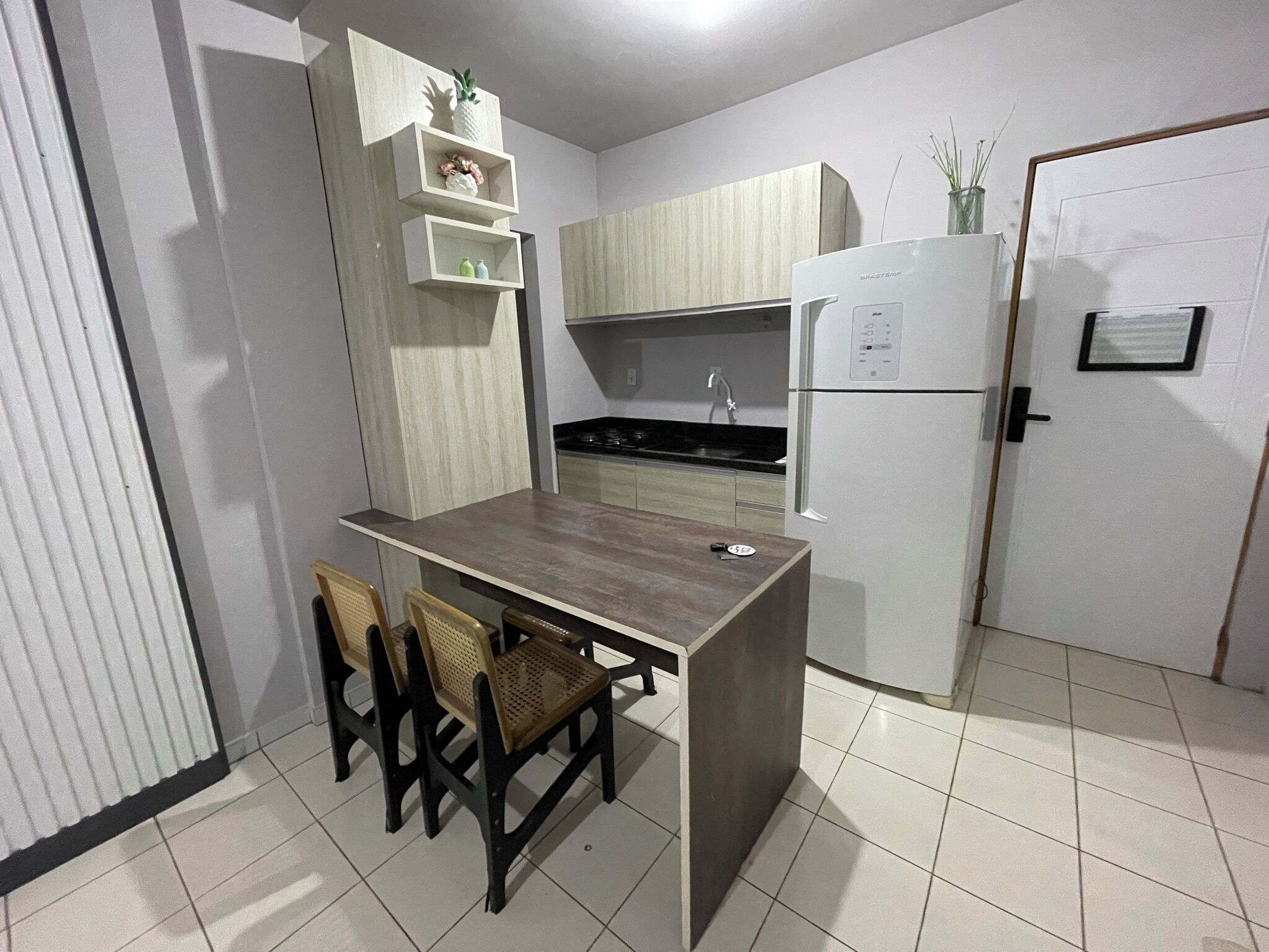 Una cocina compacta con una isla central, un refrigerador, una estufa y un lavamanos. Hay dos sillas en la isla.