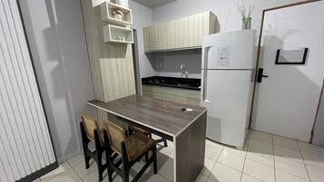 Una cocina compacta con una isla central, un refrigerador, una estufa y un lavamanos. Hay dos sillas en la isla.