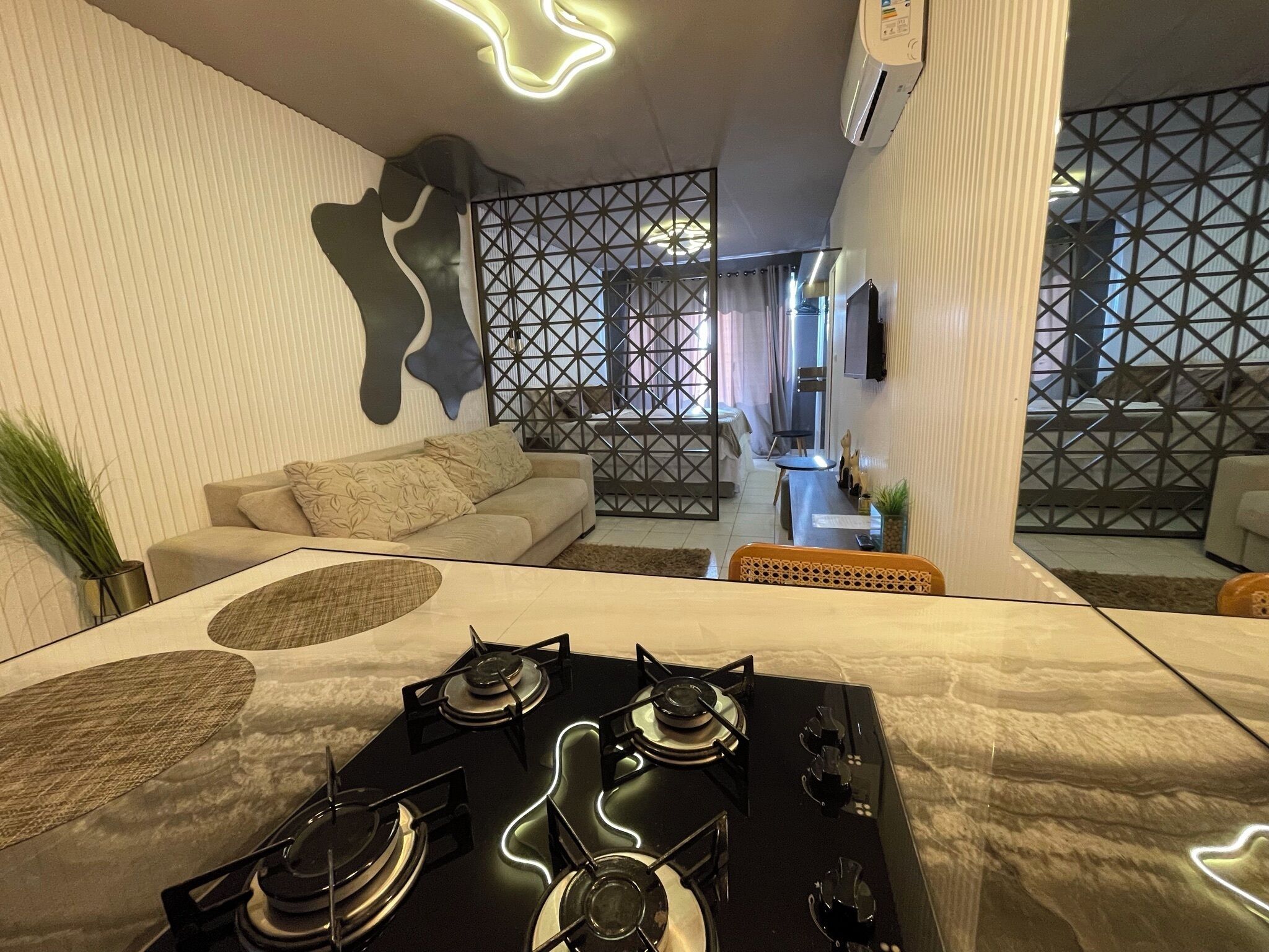 A modern kitchen with a gas stove, a dining area with a sofa and a decorative wall.