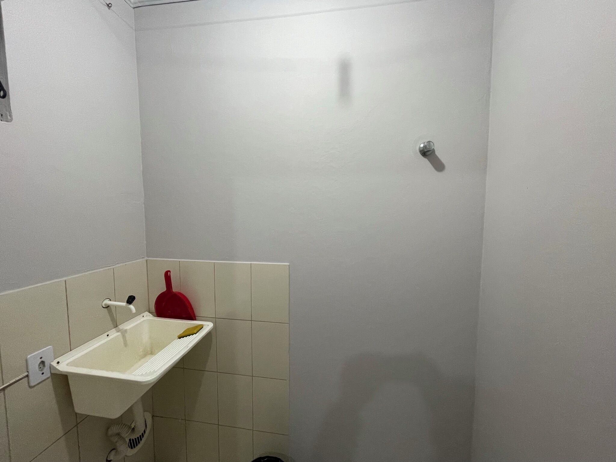 A small, clean bathroom with a white sink, a red fire extinguisher, and a shower.