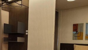 A modern hotel room with a large bed, a flat-screen TV, a bedside table, and a large mirror reflecting the room.