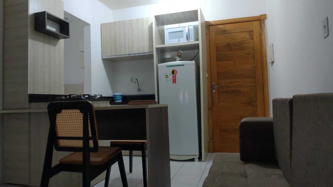 A compact kitchen with a microwave, refrigerator, and a wooden door.