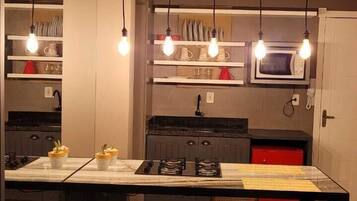 A modern kitchen with a central island, overhead lighting, and built-in appliances.