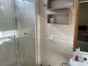 Bathroom features a glass-enclosed shower area and a clean, contemporary design.