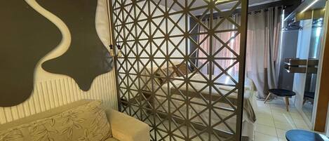 A modern living room with a beige sofa, a geometric patterned partition, and a small round table.