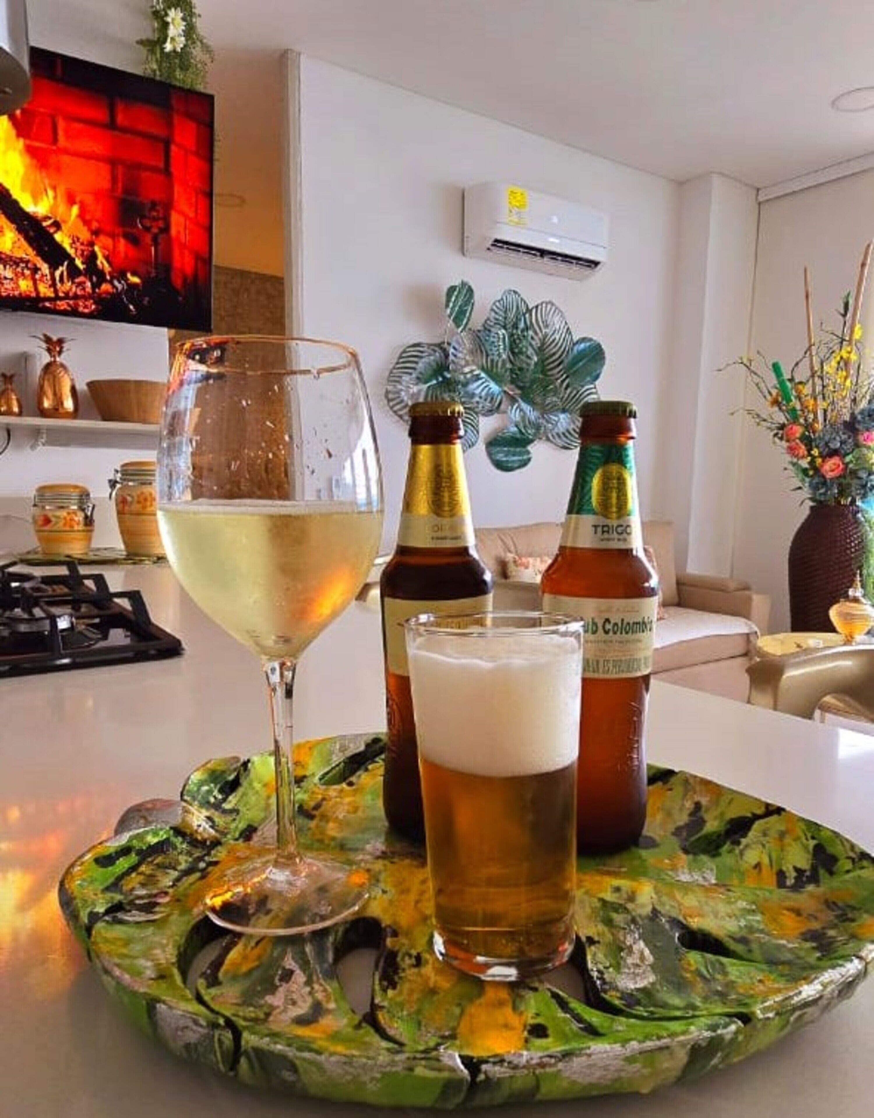 A bar area with a glass of white wine, two bottles of beer, and a decorative plate.