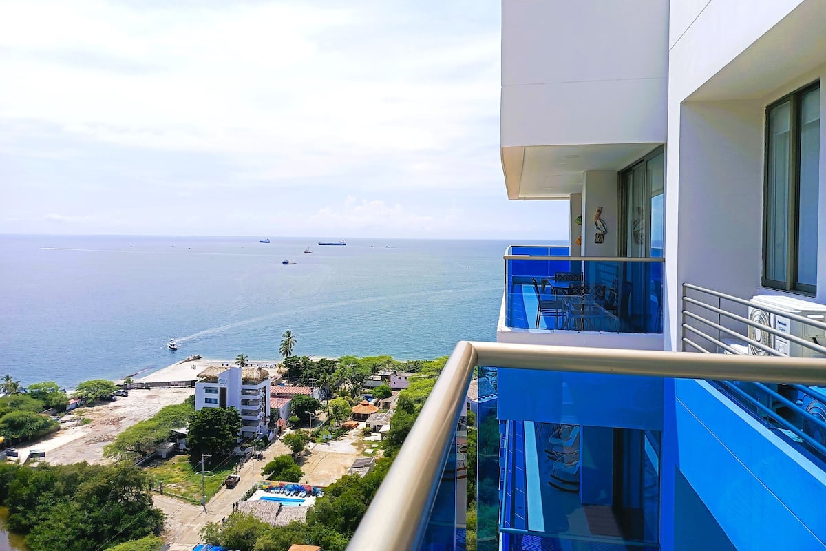 Ein Hochhaus mit Balkon mit Blick auf eine Küstenlandschaft, Schiffe und einen Strand.