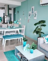 Una cocina moderna con armarios blancos, una campana de acero inoxidable y una pared azul verdoso decorada con motivos náuticos.