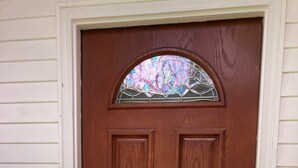 A wooden door with a glass panel and a keypad lock.