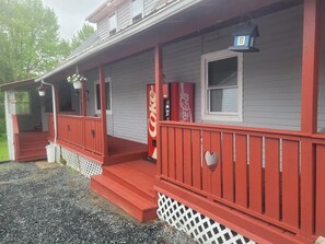 A two-story house with a red porch and a Coca-Cola vending machine.