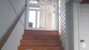 A wooden staircase leading to a door with a glass door and a window with a stained glass design.