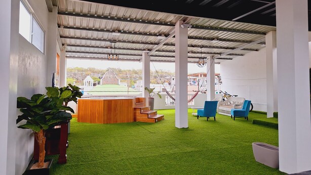 An outdoor patio with artificial grass, a wooden bench, and a hammock.
