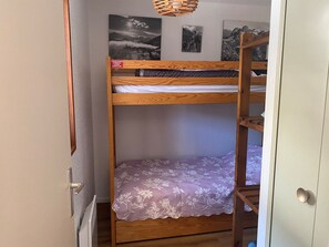 A bunk bed with a floral bedspread and a wooden headboard.