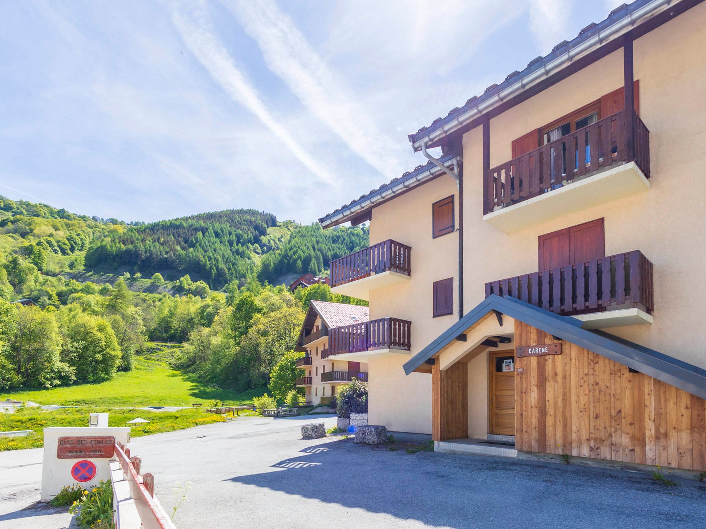 A hotel with a wooden facade, balconies, and a view of a green valley.