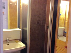 A bathroom with a sink, mirror, and shower enclosure.