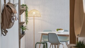 A dining area with a white table, two chairs, a floor lamp, and potted plants. - Funchal Holidays, near the beach - Lido View Calla (Funchal)
