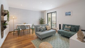 A modern living room with a grey sofa, a dining table with chairs, a floor lamp, and a patterned rug. - Funchal Holidays, near the beach - Lido View Calla (Funchal)