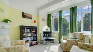 Ein Wohnzimmer mit floralen Ohrensesseln, einem Bücherregal und einem Fernseher.